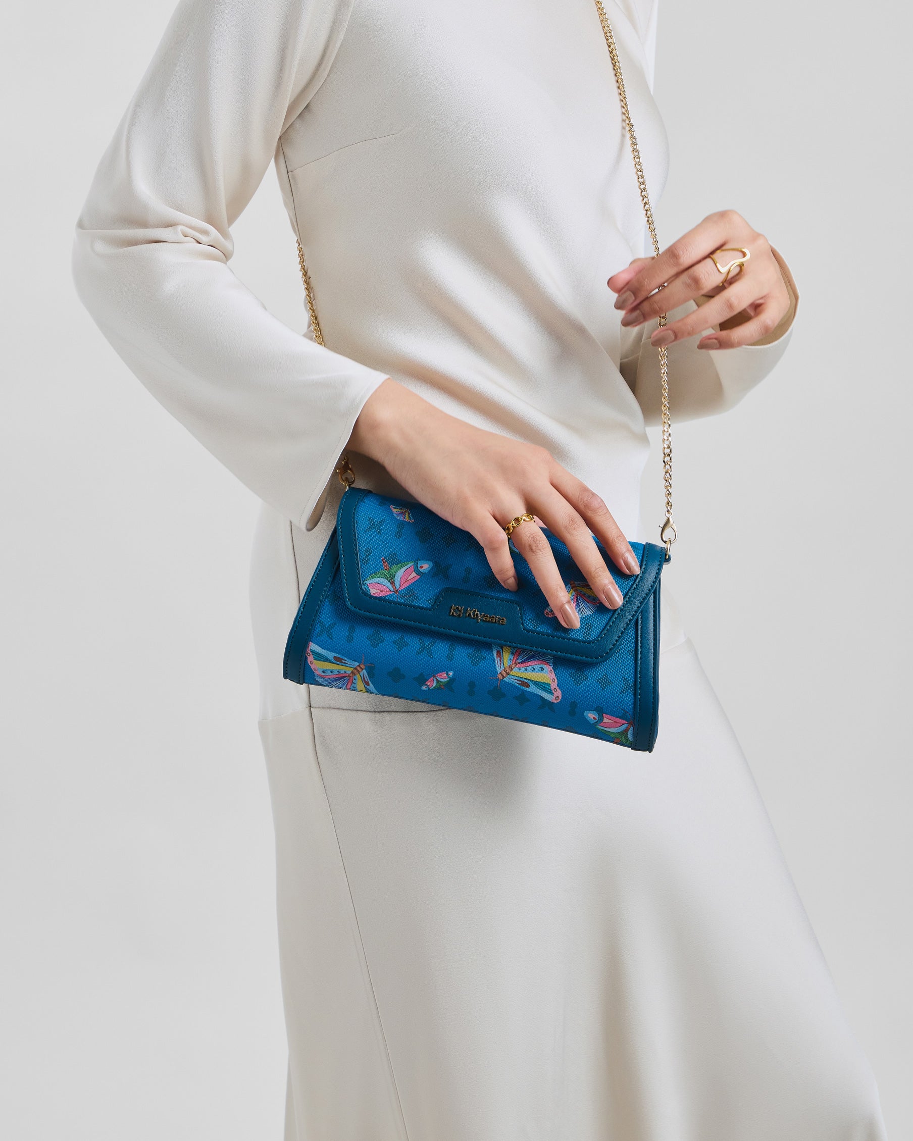 Flutter Clutch Bag by House of Kiyaara in hand-painted vegan leather, held against a simple plain white summer outfit showing how one statement clutch transforms a minimal look